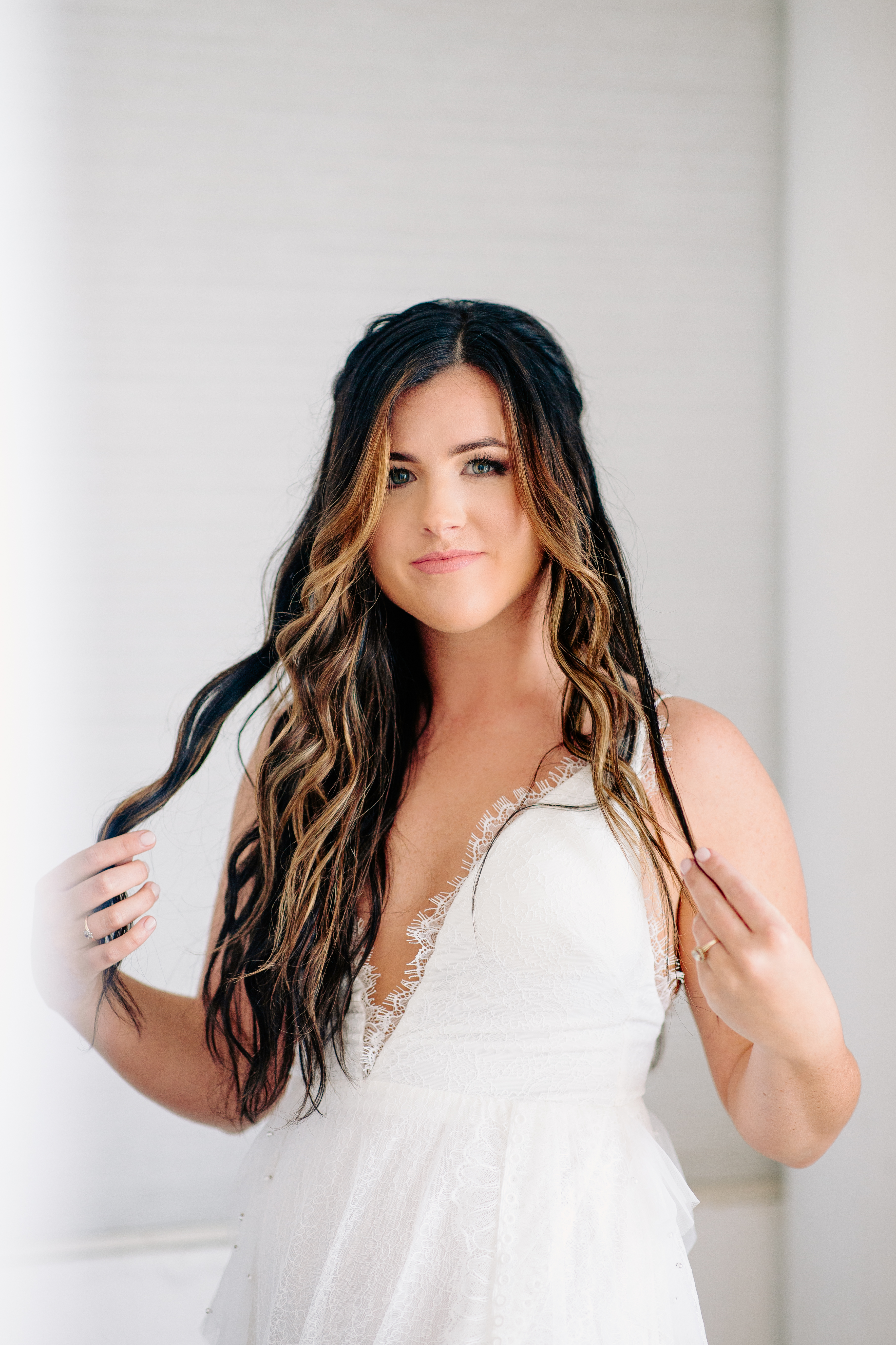 Bride in a lace v-neck wedding gown with long wavy hair, looking directly at camera, photographed by Weddings by Wendi