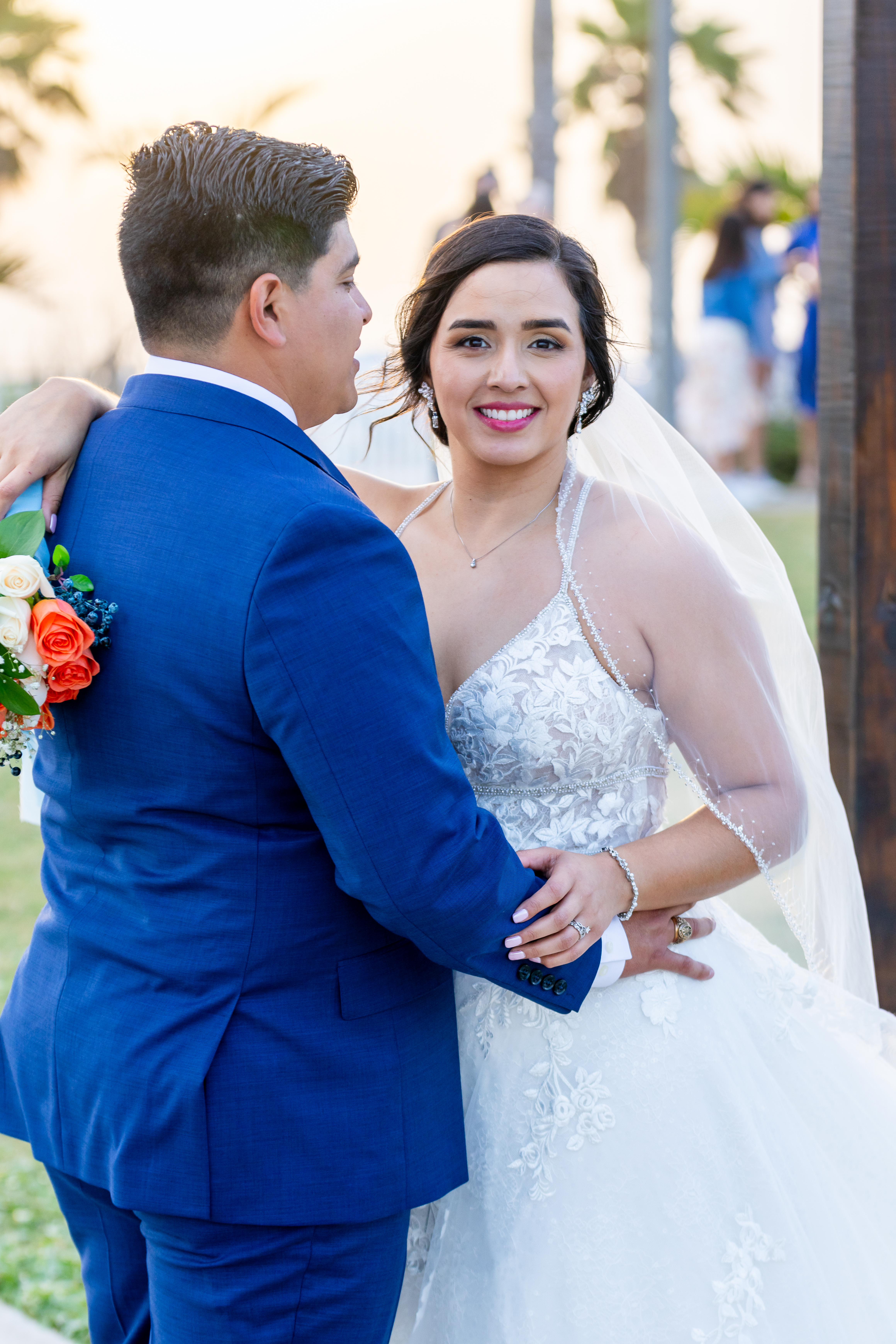 Bride smiling joyfully at her groom during golden hour with palm trees in the background, photographed by Weddings by Wendi