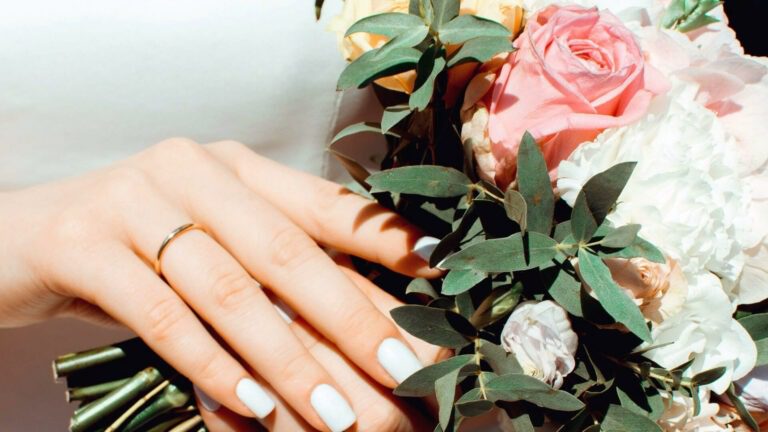 a woman's hands with white nails and flowers