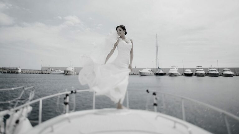 a woman in a white dress is standing on a boat