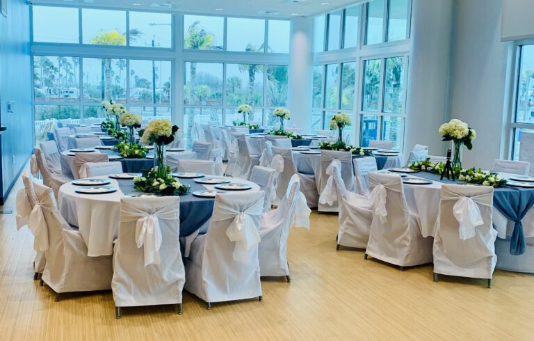 a room filled with tables covered in white and blue cloths