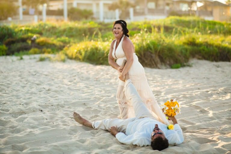 a bride and groom laying on the beach