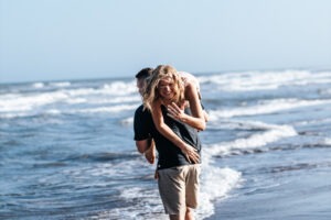 a man carrying a woman on his back at the beach