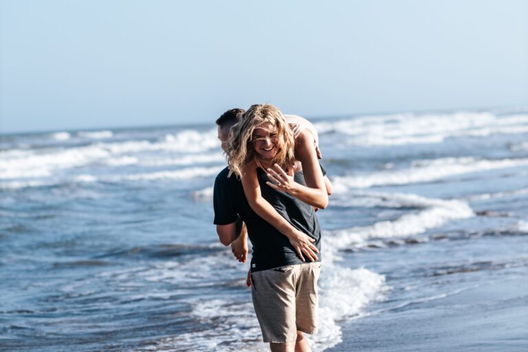 a man carrying a woman on his back on the beach