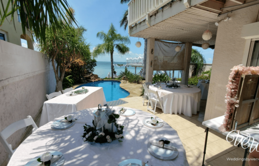 a table set up for a formal dinner by the pool
