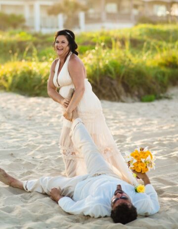 a bride and groom laying on the beach