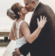 a bride and groom kissing on a dock