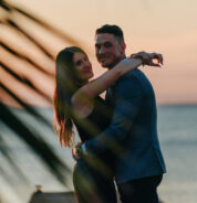 a man and a woman standing next to each other near the ocean