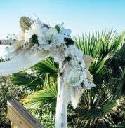 a wedding arch decorated with white flowers and feathers