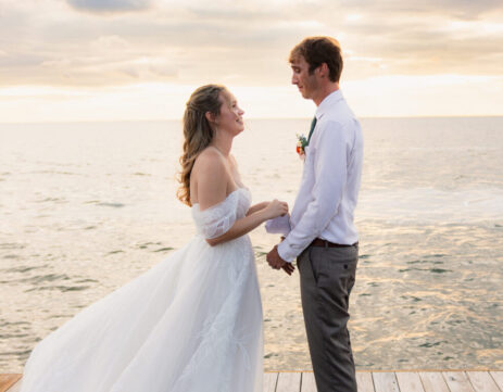 a man and woman standing on a dock by water