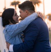 a man and a woman embracing each other in front of a white picket fence