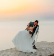 a bride and groom kissing on a dock