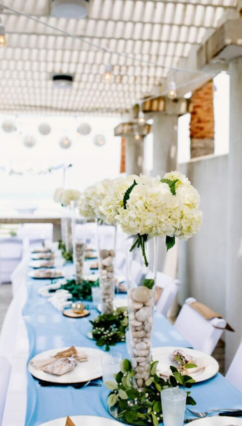 a long table with white flowers and rocks on it