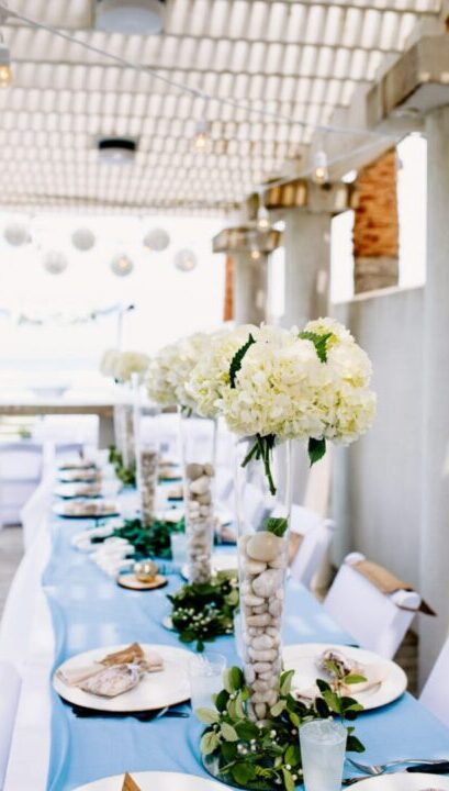 a long table with white flowers and rocks on it