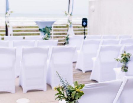 an outdoor wedding setup with white chairs and flowers
