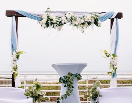 an outdoor ceremony setup with white chairs and flowers