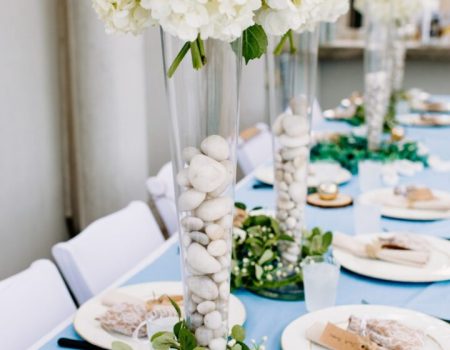 a long table with white flowers and plates on it