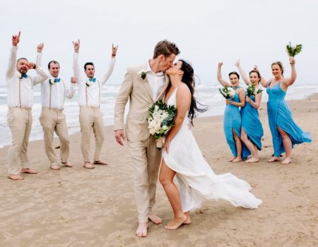 a bride and groom kissing on the beach