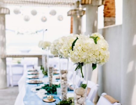 a long table with white flowers and rocks on it