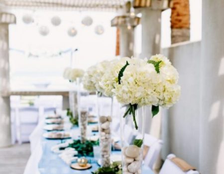 a long table with white flowers and rocks on it