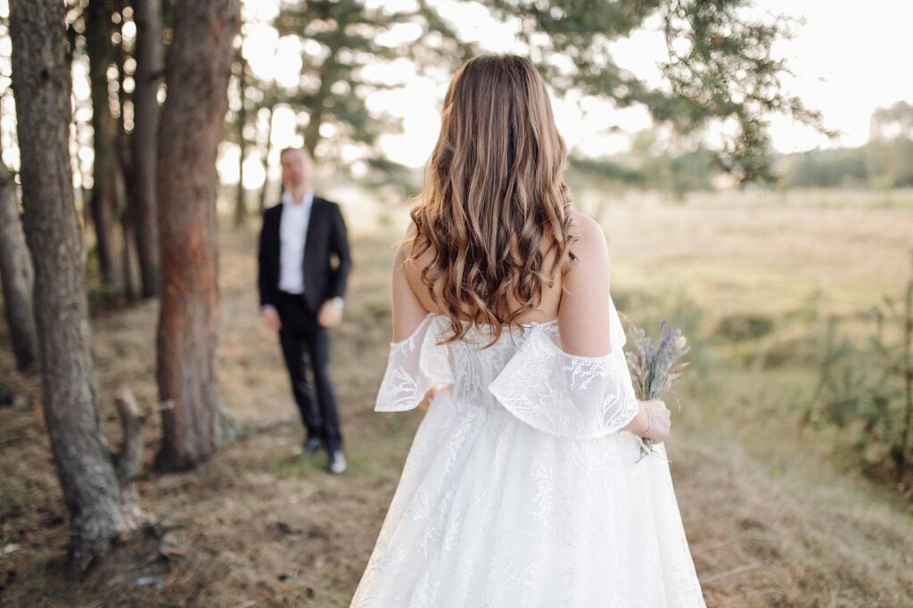 Full Wedding Planning - Weddings By Wendi Bride in a flowing white gown holding lavender, gazing at her groom in a serene Texas Hill Country setting.