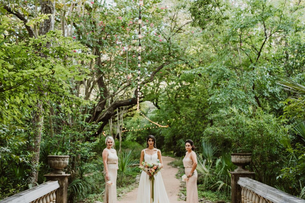 Bridesmaids posing with the bride in a lush green garden setting, Austin, TX.