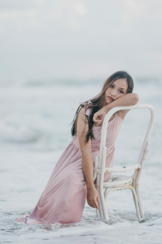 woman wearing pink dress sitting on white chair How to Pose for Amazing Wedding Pictures