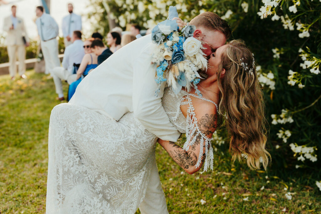 a bride and groom kissing in front of a group of people