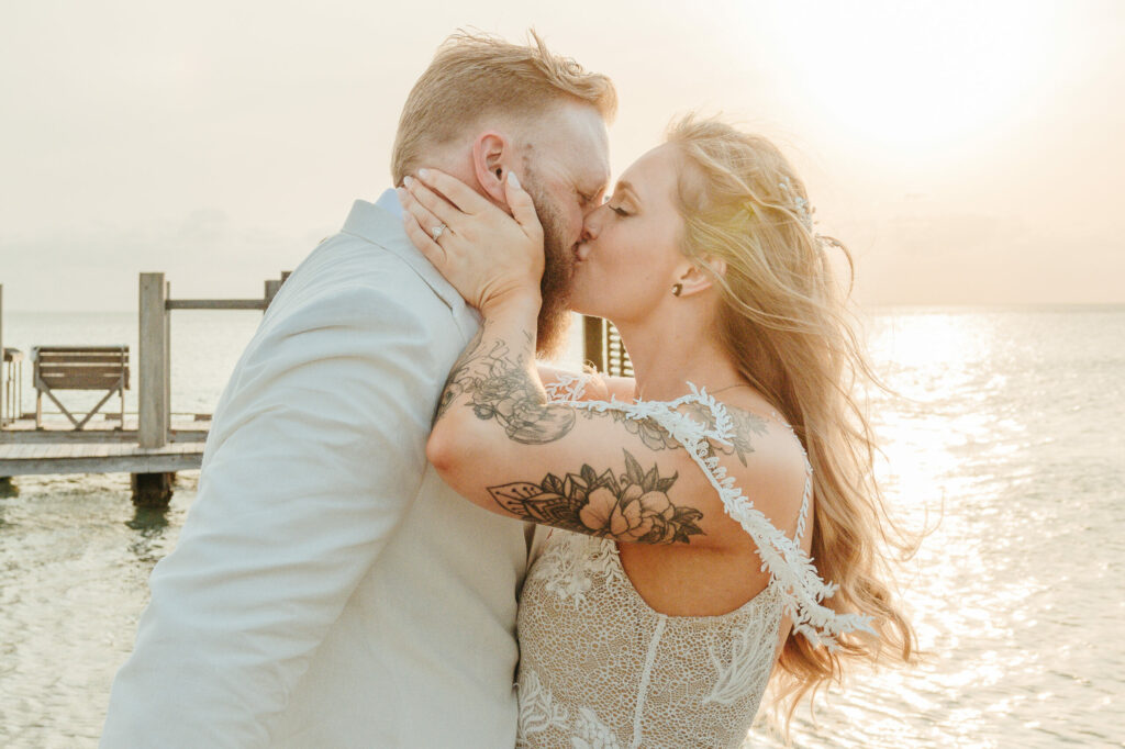 a man and woman kissing in front of the ocean