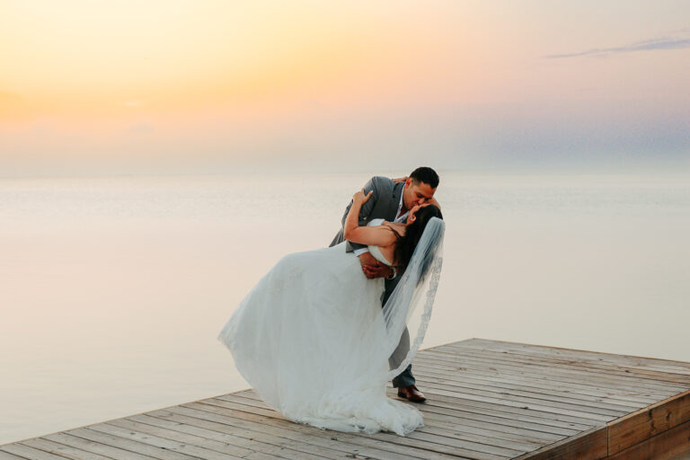 a bride and groom kissing on a dock