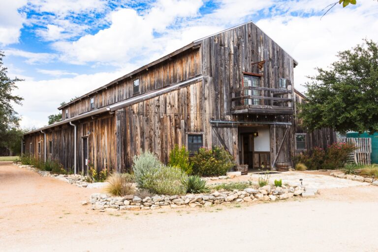 a wooden barn with a blue sky and clouds