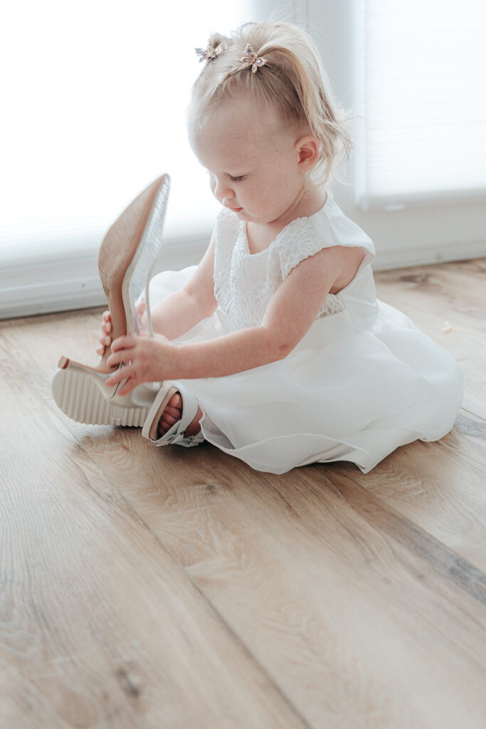 Full Wedding Planning - Weddings By Wendi a baby in a white dress holding a shoe